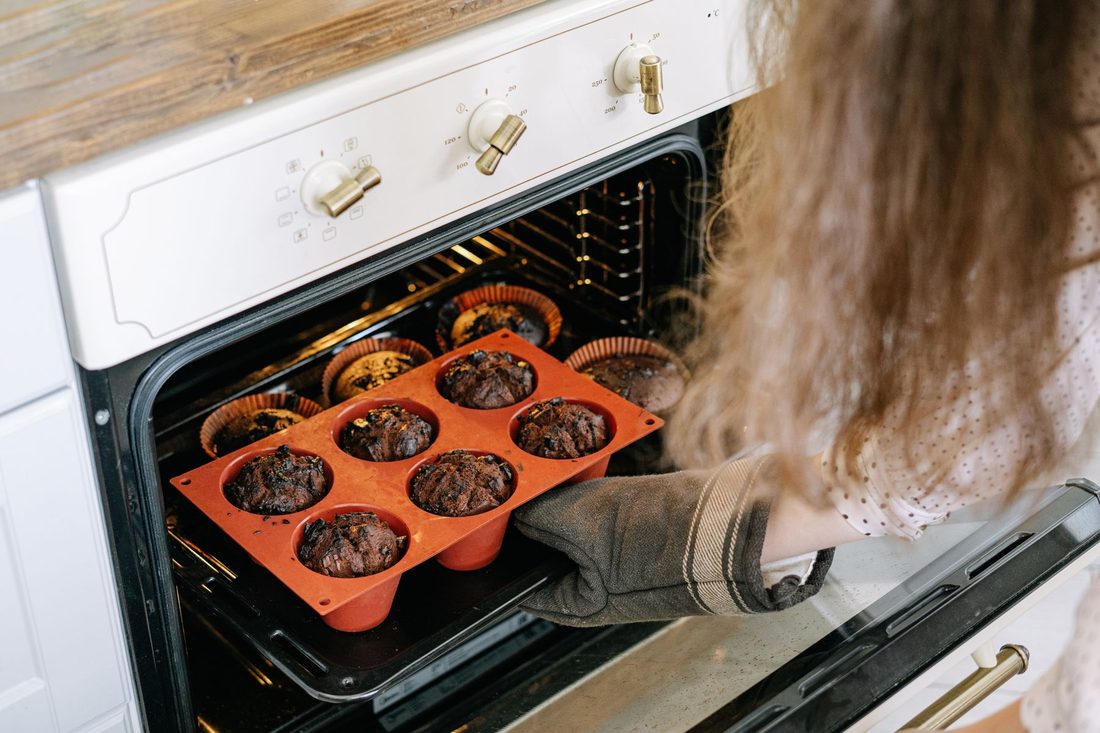 A tray of muffins going into the oven: opening the door too early is one of the reasons why cakes sink