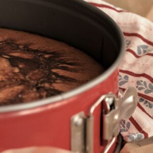 A freshly baked chocolate cake in a red springform pan, before it is turned out